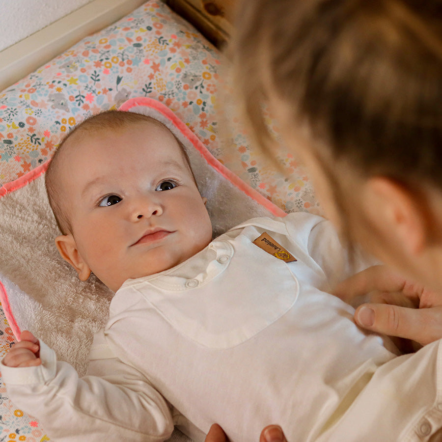 Mutter zieht Baby den Löwenkind-Body an